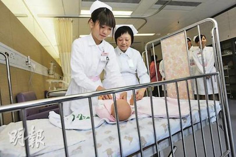 浸會醫院護士學校，由九龍塘搬到牛頭角工業區一座工商業大廈繼續授課。明年4月畢業的二年級學生梁詠欣（左），在導師指示下學習照顧嬰兒，希望畢業後能在兒科病房服務。（朱永倫攝）