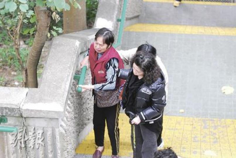 因中風不良於行的鍾老太（左），短短半年間痛失丈夫及愛子，縱然要由親友攙扶上落樓梯，仍堅持到天馬苑球場拜祭亡兒。（何朝財攝）