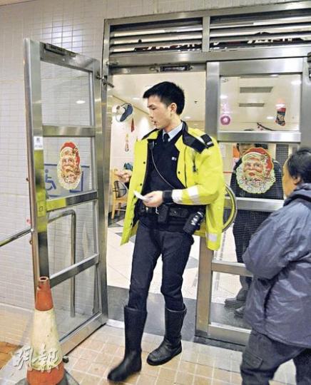 事後保安員將閘門綁緊於扶手柄等候維修，警員到場調查，列作有人意外受傷處理。（樊銳昌攝）閘門脫鉸意外中，後備鋼鏈發揮功效將閘門拉着，未有造成嚴重傷亡。（樊銳昌攝）