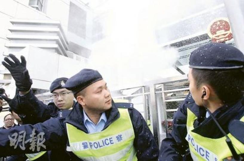站在中聯辦門外的數名警員，首當其衝「中奶粉彈」，事後有兩人報稱眼部不適須送院治理。（林振東攝）擔任「長毛」梁國雄助理的姜靈彰，手持裝有奶粉的膠袋，將之拋進中聯辦內。（林振東攝）中聯辦正門的國徽亦被殃及，不過法律界人士認為，示威者非有意侮辱國徽未必可引用《國徽法》提出檢控。（林振東攝）