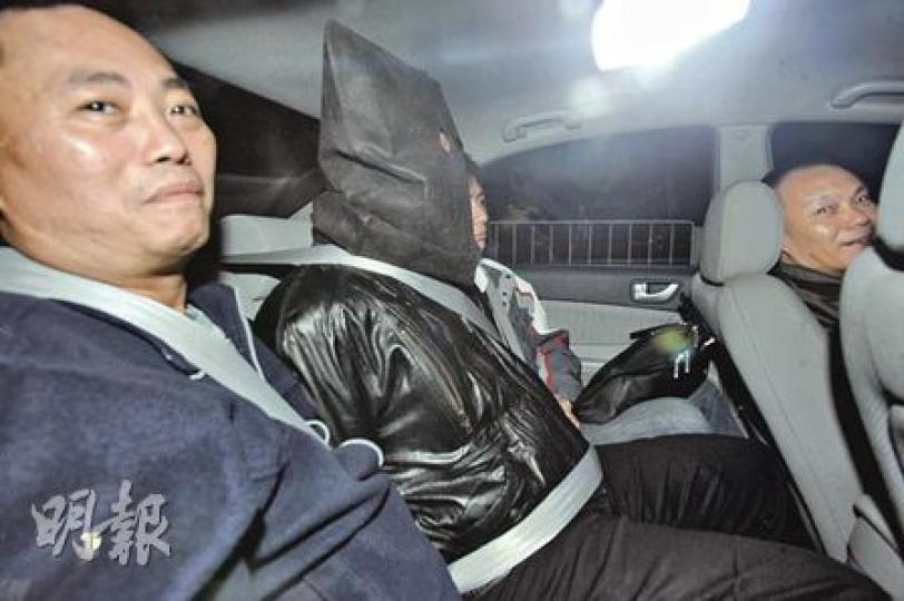 涉嫌扑頭劫殺芭蕾舞學校校長徐滿芬的冷血疑匪，被黑布蒙頭、戴上手銬及在兩名重案組探員押解下由私家車載往警署扣查。（樊銳昌攝）