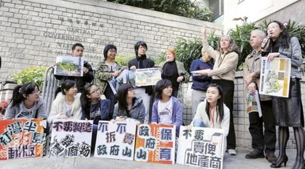 環保觸覺項目經理何嘉寶（後左二）指拆卸政府總部西座產生的建築廢料足以填滿32.5個泳池。環保觸覺昨聯同公共專業聯盟、中西區關注組、社區發展動力培育及立法會議員陳淑莊（後右一）等，在政府總部西座門外請願，反對拆卸西座建商場。（劉焌陶攝）