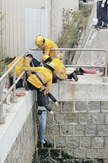 數名消防員將在碼頭邊「笨豬跳」吊頸男子扯回岸邊。（黃雄攝）