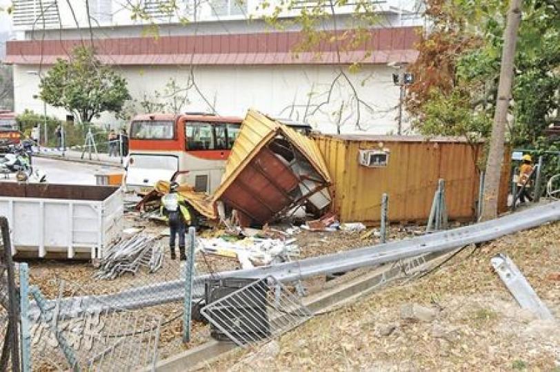 旅遊巴撞毁防撞欄和鐵絲網,沿山坡直衝入巴士廠空地,撞毁環保斗(左)和擺放雜物的貨櫃箱(中)。(衛永康攝) 旅遊巴撞毁防撞欄和鐵絲網,沿山坡直衝入巴士廠空地,撞毁環保斗(左)和擺放雜物的貨櫃箱(中)。(衛永康攝)