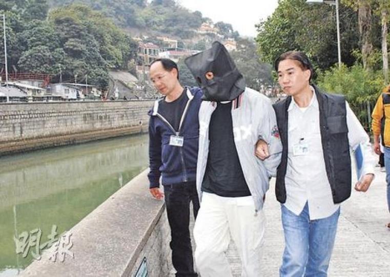 被捕男子昨午被黑布蒙頭及鎖上手扣,由探員押返大埔林村河近太和邨一段,了解他棄置行劫用萬用刀的位置及過程。(雲錦鋒攝) 被捕男子昨午被黑布蒙頭及鎖上手扣,由探員押返大埔林村河近太和邨一段,了解他棄置行劫用萬用刀的位置及過程。(雲錦鋒攝)