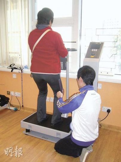 中風病人站在「重力振動器」，膝蓋要保持一定角度，振動器可刺激骨細胞及肌肉收縮及增加關節內的壓力感應，改善中風病人的肌肉力量。（黃靜雅攝）