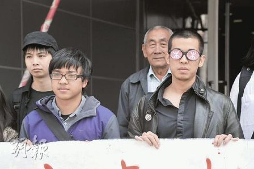 菜園村巡守隊員林崑傑（左二）及陳寧（右一）被控毁壞菜園村工地的鐵絲圍網，兩人否認控罪，陳戴上有港鐵標誌的眼鏡遮蔽雙眼，諷刺港鐵為高鐵工程「連隻眼都盲咗」。（葉漢華攝）
