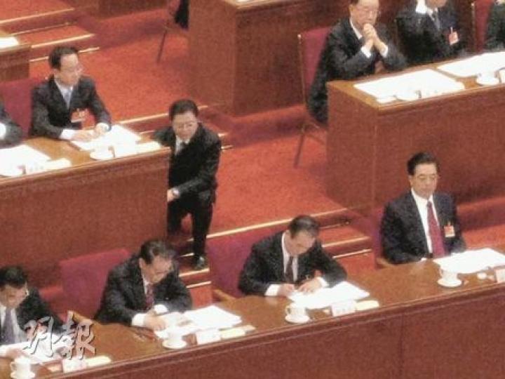 溫總（前右二）在字條上奮筆批示時，工作人員半蹲在令計劃（後左一）座位旁等待。（明報記者攝）溫總批示完後，胡總（前右一）將文件交還給工作人員（前右二）。（明報記者攝）