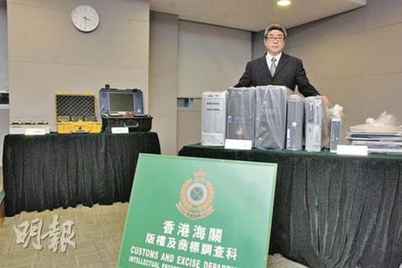 海關版權調查組指揮官關煜群展示檢獲的電腦伺服器及電腦。（雲錦鋒攝）（明報製圖）