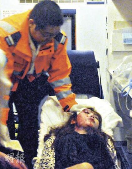 公主道私家車炮彈飛車車禍中，一名的士女乘客飛來橫禍，臉部無辜受傷，她被送上救護車後救護員努力助她止血。（蔡方山攝）