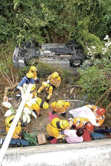 客貨車在黃泥涌峽道衝落約6米下山坡，四輪朝天，其中女傷者（粉紅衣）由消防員救出。（屈俊樂攝）客貨車在半山黃泥涌峽道失控剷上行人路，撞毁路邊鐵欄後衝下約6米山坡。（黃雄攝）