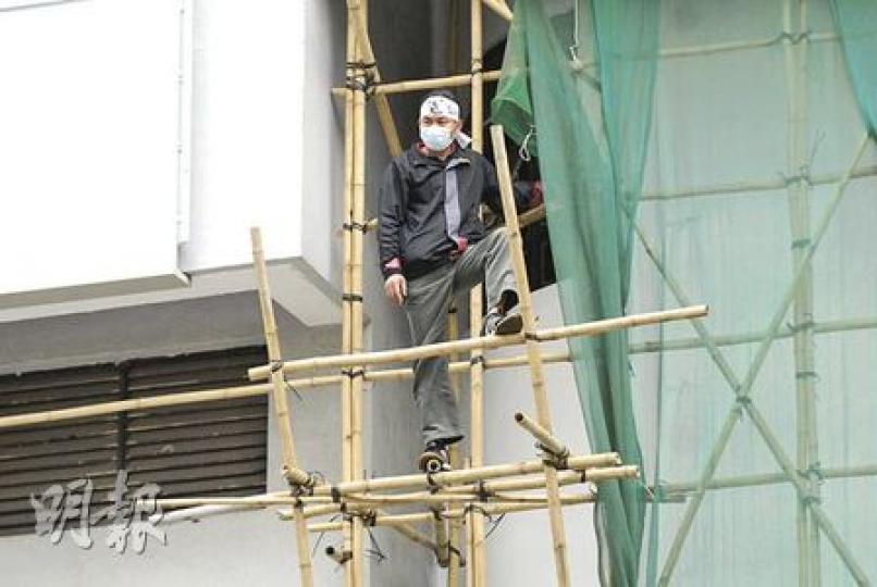 申冤男子頭纏「冤」、「死不瞑目」標語危站在東區法院棚架，擬以死控訴，與警對峙5小時後返回地面。（梁琬珊攝）為亡妻申冤的男子，危站在東區法院棚架擬以死控訴（箭嘴示），消防到場張開救生氣墊戒備。（雲錦鋒攝）