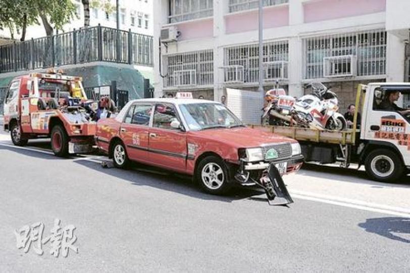倒楣的士司機昨早撞車後，把的士駛至紅磡一間車房維修，修畢後隨即與警方鐵馬相撞損毁，的士事後被拖走調查。（樊銳昌攝）