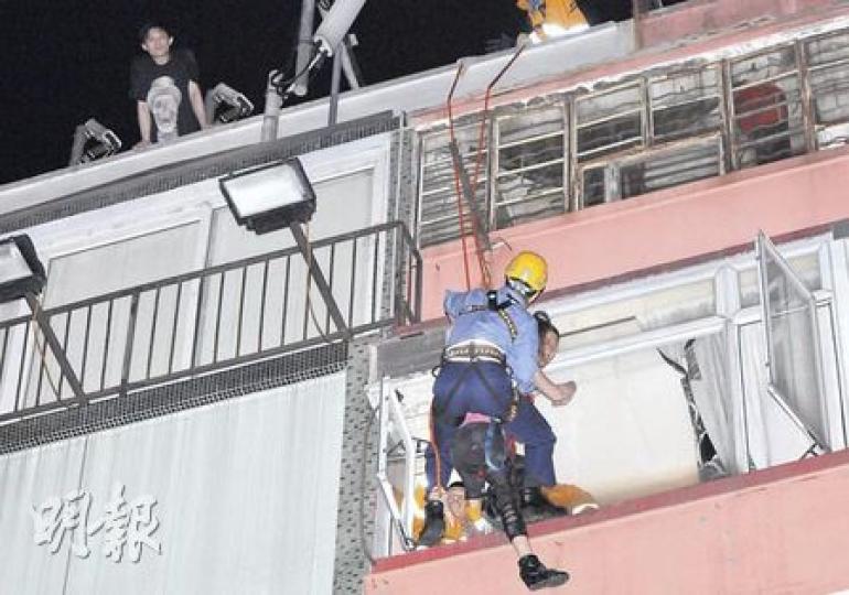 消防「飛將軍」拯救企圖跳樓女子，場面異常驚險。女事主男友（左上角）一直在天台凝望女友情况。（蔡方山攝）女子危坐耀華街唐樓4樓單位冷氣機頂（箭嘴示），大批消防員到場拯救，氣氛一度緊張。（蔡方山攝）