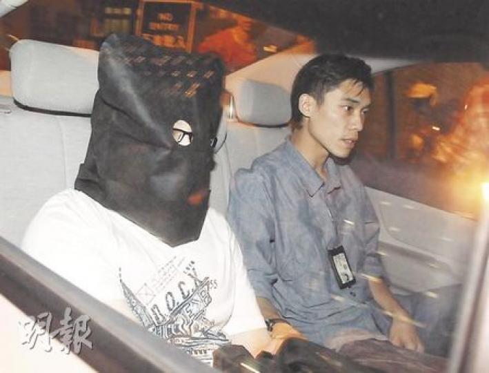 涉用改裝購物袋暗藏攝錄器材偷拍裙底春光的疑犯，被黑布蒙頭帶返警署調查。（衛永康攝）