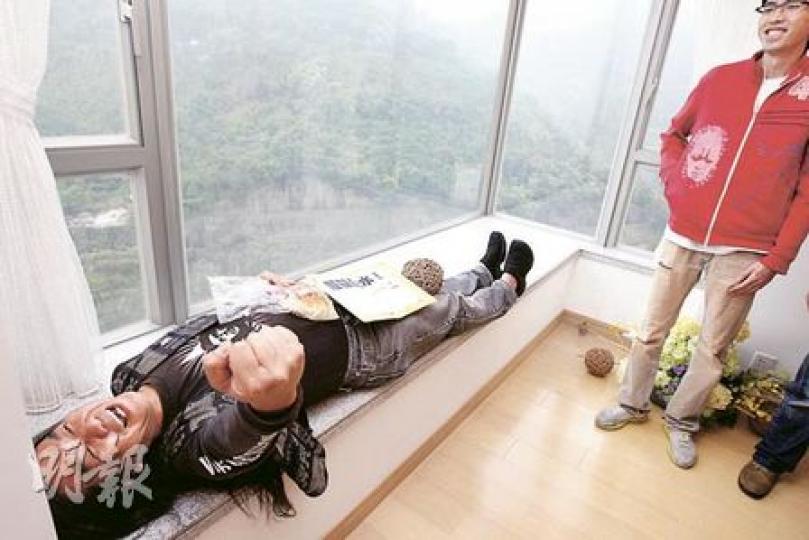 立法會議員梁國雄（左）聯同社民連10多名成員，昨日到大圍樓盤名家匯「踩場」，其間長毛整個人橫卧窗台，揶揄發展商大建發水樓，又預告狙擊地產商的行動會陸續有來。（李紹昌攝）