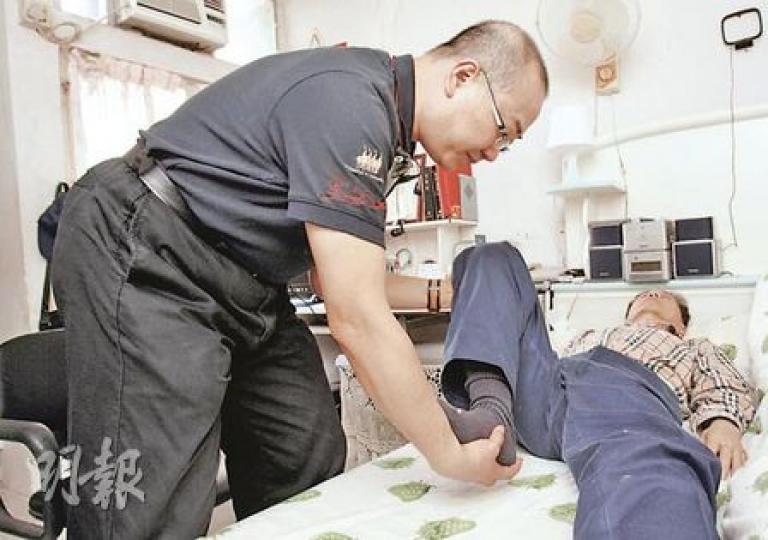 趙崇偉(左一)學習按摩課程後,由生意人變身按摩員,為70歲的郭伯伯(躺臥者)治療坐骨神經痛,經十多次按摩治療後,伯伯原本無法彎曲的膝蓋已恢復活動能力。(陳智良攝) 趙崇偉(左一)學習按摩課程後,由生意人變身按摩員,為70歲的郭伯伯(躺臥者)治療坐骨神經痛,經十多次按摩治療後,伯伯原本無法彎曲的膝蓋已恢復活動能力。(陳智良攝)