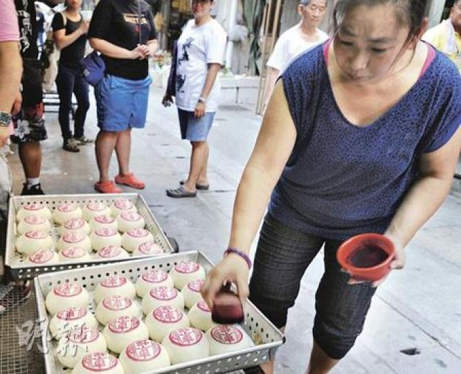面對今年平安包風波,平安包店「康蘭」繼續按傳統方法趕工,並在店門外為一籠籠蒸好的平安包蓋印。 (尹錦恩攝) 面對今年平安包風波,平安包店「康蘭」繼續按傳統方法趕工,並在店門外為一籠籠蒸好的平安包蓋印。 (尹錦恩攝)
