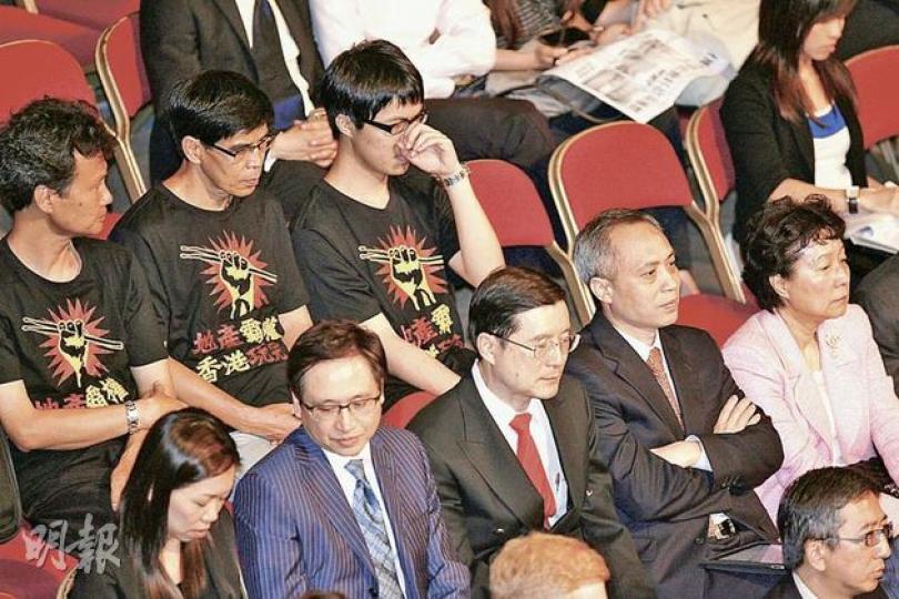美孚部分業主(穿黑色T恤者)繼續「追擊」被他們認為欲於屋苑內建「屏風樓」的新世界,昨在賣地場坐在新世界代表的後方。(郭慶輝攝) 美孚部分業主(穿黑色T恤者)繼續「追擊」被他們認為欲於屋苑內建「屏風樓」的新世界,昨在賣地場坐在新世界代表的後方。(郭慶輝攝)