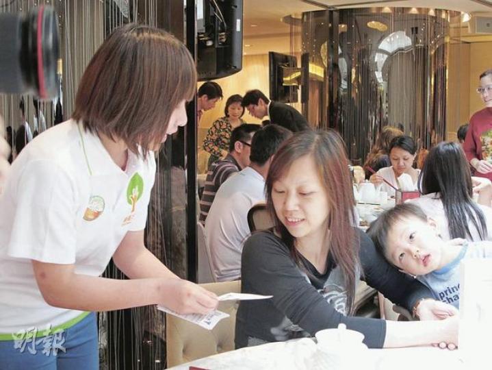 綠領行動「有衣食大使」樊雪彤(白衫)日前到鴻星旺角分店實習,她說酒樓顧客浪費食物的情况沒想像中嚴重,圖為她向顧客宣傳珍惜食物信息。(余卓善攝) 綠領行動「有衣食大使」樊雪彤(白衫)日前到鴻星旺角分店實習,她說酒樓顧客浪費食物的情况沒想像中嚴重,圖為她向顧客宣傳珍惜食物信息。(余卓善攝)