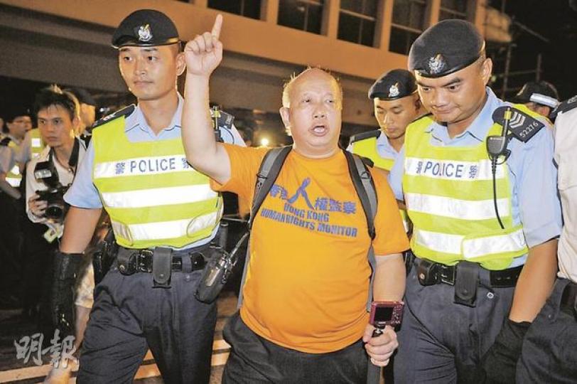 七一後的凌晨，香港人權監察總幹事羅沃啟在中環干諾道中觀察警方清場行動，突遭兩名警務人員阻撓，一度企圖把他帶離現場送上警車。（何家達攝）