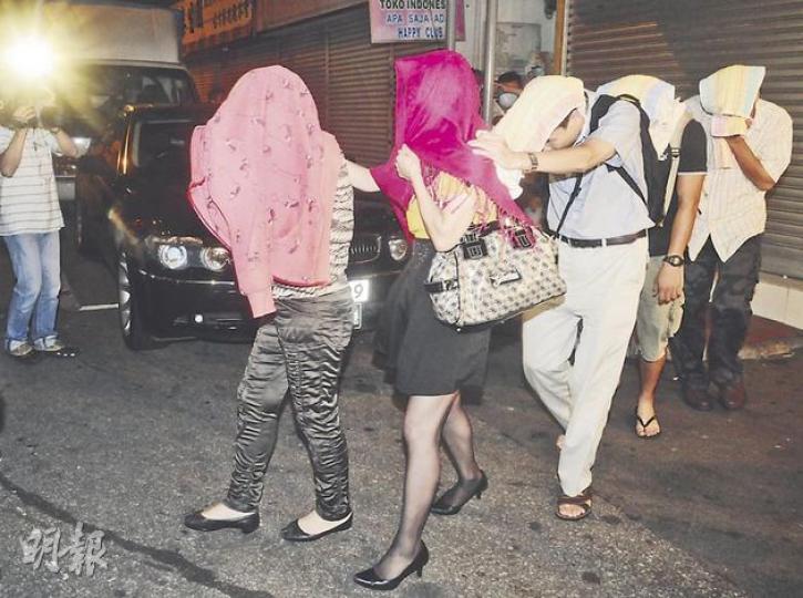 多名男女涉嫌非法聚賭帶署,被帶走時以外套和毛巾遮蓋臉容。(蔡方山攝) 多名男女涉嫌非法聚賭帶署,被帶走時以外套和毛巾遮蓋臉容。(蔡方山攝)