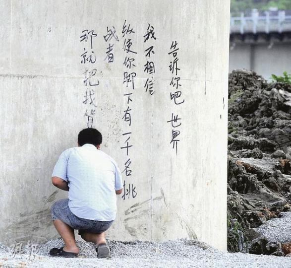 有身穿T恤短褲的中年男子,在現場橋墩寫上新詩,其後被公安帶走。(余俊亮攝) 有身穿T恤短褲的中年男子,在現場橋墩寫上新詩,其後被公安帶走。(余俊亮攝)