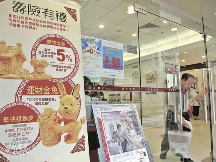 有銀行在門外以大型易拉架推銷中國人壽保險(海外)的產品,以24K包金金兔、家肥屋潤包金擺設,以及46吋大電視招徠。(陳佩儀攝)蘇黎世人壽保險與代理銀行以投保送金碗作推廣,銀行特別以玻璃飾櫃展示金碗擺設。(劉焌陶攝) 有銀行在門外以大型易拉架推銷中國人壽保險(海外)的產品,以24K包金金兔、家肥屋潤包金擺設,以及46吋大電視招徠。(陳佩儀攝)蘇黎世人壽保險與代理銀行以投保送金碗作推廣,銀行特別以玻璃飾櫃展示金碗擺設。(劉焌陶攝)