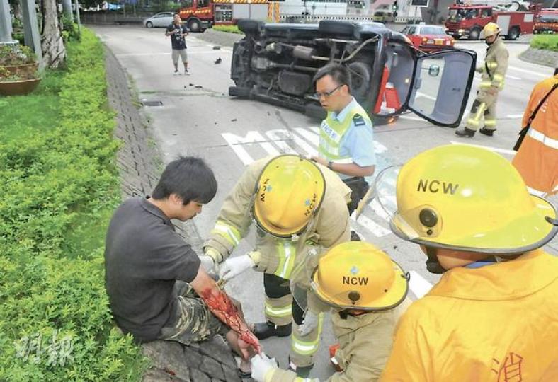 穿拖鞋的私家車司機,事後坐在路邊接受消防包紮手臂,其座駕剷上花槽後翻側。(蔡方山攝) 穿拖鞋的私家車司機,事後坐在路邊接受消防包紮手臂,其座駕剷上花槽後翻側。(蔡方山攝)