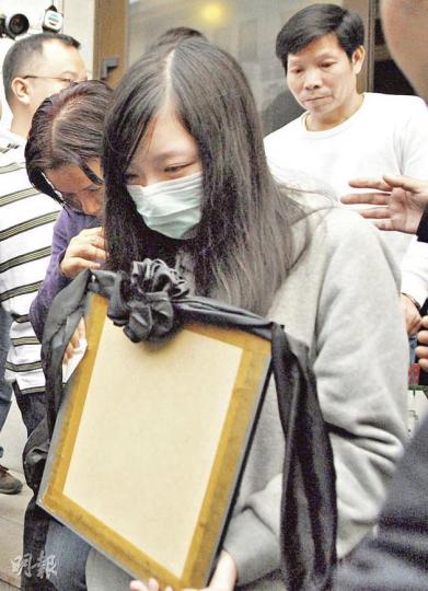 19歲少女（灰衣者）與父親（白衣者）昨到八寶山公墓送別亡母，離開時故意把母親遺照反轉貼近身體，神情哀傷。（梁琬珊攝）