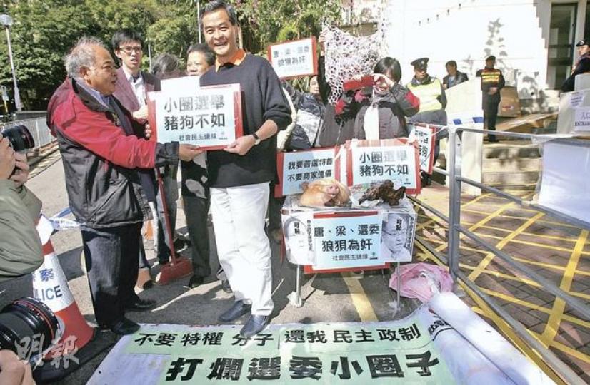 參選政協界別選委的政協常委梁振英(穿白褲者),昨日到山頂投票,遭社民連成員狙擊,反對特首小圈子選舉,對方帶了生豬頭和熟豬頭,以示唐梁當選也是一樣。梁振英接信後,示威者對他拋擲紙碎。(林振東攝) 參選政協界別選委的政協常委梁振英(穿白褲者),昨日到山頂投票,遭社民連成員狙擊,反對特首小圈子選舉,對方帶了生豬頭和熟豬頭,以示唐梁當選也是一樣。梁振英接信後,示威者對他拋擲紙碎。(林振東攝)