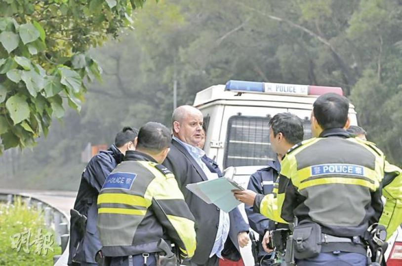 寶馬房車的外籍男司機(中)拒絕進行酒精呼氣測試,事後「氣定神閒」隨警員登上警車帶署。(林錫禮攝) 寶馬房車的外籍男司機(中)拒絕進行酒精呼氣測試,事後「氣定神閒」隨警員登上警車帶署。(林錫禮攝)