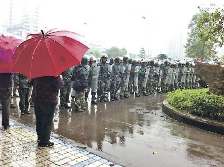 大批重慶萬盛區民眾昨冒雨到廣場聚集，抗議當局把萬盛區與綦江區合併，大批手持盾牌的警員組成人鏈驅散人群。（明報記者攝） 公安車輛停在路邊戒備。（明報記者攝） 萬盛區大小商舖昨日被勒令拉閘停業。（明報記者攝）