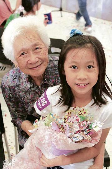 梁太﹙左﹚含辛茹苦養育的10名子女均已出身，其孫女﹙右﹚趁母親節親手用彩紙摺出花朵，送贈婆婆。（鄭宏禮攝）