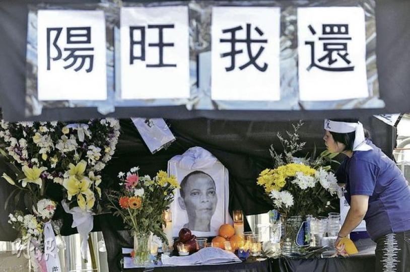 本港有團體昨日在中聯辦外為被指「自殺」的民運人士李旺陽設靈（圖），但附近的均益大廈3期立案法團成員掛起橫額抗議。團體表示，將靈位設於均益大廈外行人路是由警方安排，並非他們建議，呼籲居民諒解。（余俊亮攝）