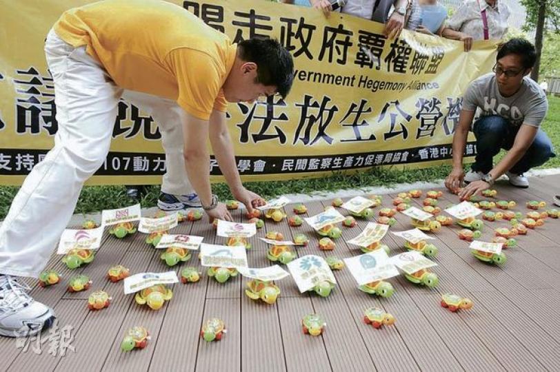 立法會昨日繼續審議競爭法，有團體在大樓外示威，並「放生」機械烏龜，諷刺草案放生公營機構。（劉焌陶攝）