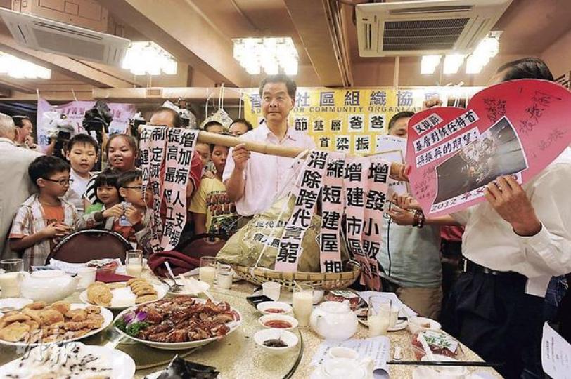 候任特首梁振英（中）收下社協送出的「擔挑」及請願信，承諾會盡快解決公屋輪候時間過長的問題。（尹錦恩攝）有小朋友向梁振英表示媽媽身在內地，未獲當局批出單程證，盼候任特首能助他與母親團聚。梁振英輕撫小孩額頭，承諾盡力協助。 （尹錦恩攝）