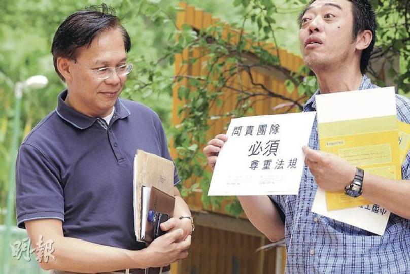 發展局長麥齊光(左)昨到東涌出席居民諮詢會前,有示威者向他遞上信件及兩本屋宇署處理違規建築的小冊子,促請各官員檢查住宅有沒有僭建物。(鄧宗弘攝) 發展局長麥齊光(左)昨到東涌出席居民諮詢會前,有示威者向他遞上信件及兩本屋宇署處理違規建築的小冊子,促請各官員檢查住宅有沒有僭建物。(鄧宗弘攝)