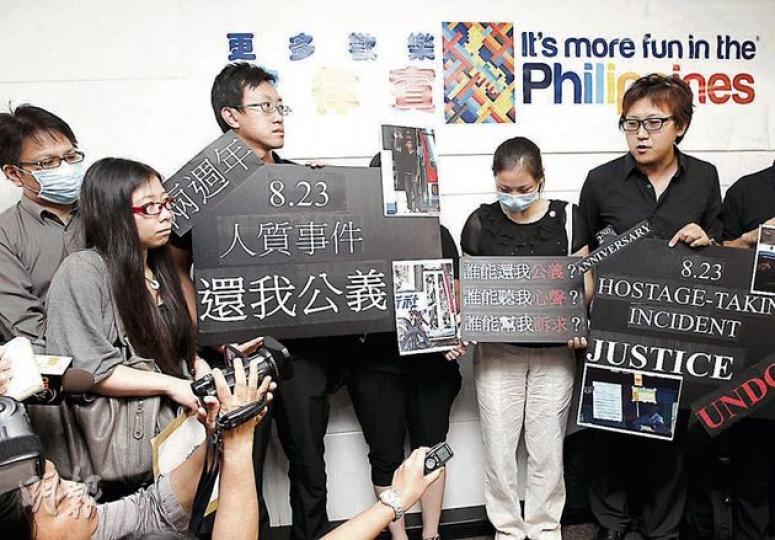 菲律賓人質事件發生兩年，部分生還團友及殉職領隊謝廷駿的家人，昨日到菲律賓駐港總領事館請願，要求討回公道。左起為：陳國柱、李瀅銓、謝志恆、易小玲、謝志堅。（李紹昌攝）生還團友易小玲，兩年來經歷20多次手術，至今仍不敢脫下口罩示人，為人質事件的死難者默哀一刻，不禁激動痛哭。（李紹昌攝）
