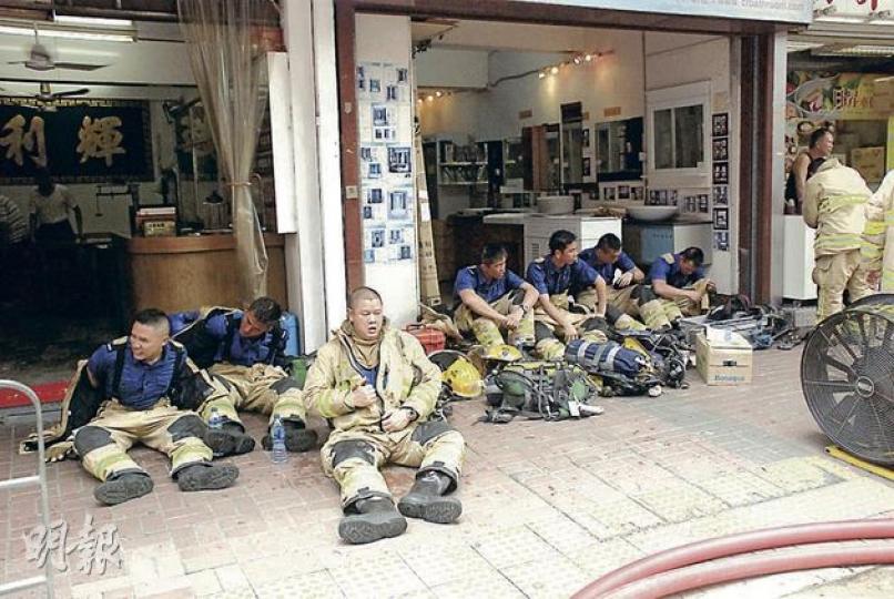 消防員昨穿梭於起火的荔枝角道14層高舊樓不斷疏散及拯救住客，大半小時後部分首批到場消防坐在地下喘氣及稍事休息，由其他同僚接力繼續救人。（雲錦鋒攝）