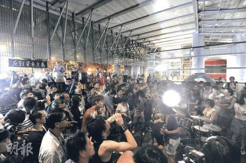 「佔領中環」昨晚在匯豐銀行中環總行地下度過「最後一夜」，但現場並無離愁別緒，60多人載歌載舞，有人大唱搖滾樂曲。（余俊亮攝） 匯豐保安員昨晚約10時張貼告示，警告「任何不遵守法院命令的佔用者可能會受到制裁」，但當時佔領者仍沉醉於歌舞中，對張貼行動毫無反應。（余俊亮攝） 主婦阿樹帶同2歲和4歲的女兒，參與中環「最後一夜」，盼讓她們感受這個清場前的自由空間，她認為匯豐不應清場，香港本已缺少公共空間。（余俊亮攝）