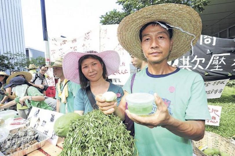 坪輋隔田村村民楊兆津（右）夫婦昨義賣自家製小食，包括手上的糯米糍及蘆薈啫喱，期望能告訴政府，農業發展有其價值。（鄧宗弘攝）