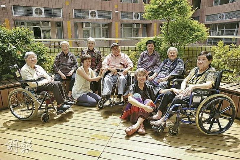 有份參展的數十名長者平均85歲，但在藝術中愈來愈有活力，笑得像孩子。左三為東華三院賽馬會復康中心藝術發展主任魏貝妮，前排坐地者為全人藝動主席梁以瑚，她們亦是今次參展藝術家之一。（葉家豪攝） 「記憶的藏寶格」（黃詠楓）- 牆上掛滿長者的肖像畫，幾個「寶箱」放置了長者的回憶片段，參觀者亦可戴上耳機，聆聽長者的「金句」、二胡演奏等。（葉家豪攝）