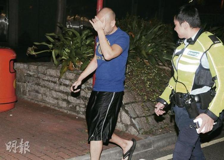 在長沙灣因車資問題涉嫌襲擊的士司機的男子（藍衣者）被警員拘捕，事後他由同行女性友人陪同帶返警署。（蔡方山攝）