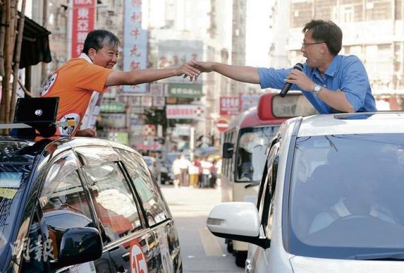 新界西候選人李卓人（左）同何君堯（右）噚日喺元朗「狹路相逢」，反而互相鼓勵對方加油，仲嚟一個「浪漫握手」。（余俊亮攝）
