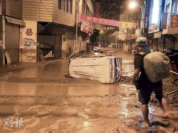 洪水湧上彝良縣城的大壩子街，多輛汽車被淹水中。（李泉攝） 災民用磚塊墊高地面以免帳篷內水浸。（李泉攝）