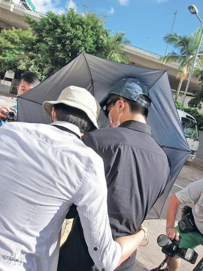 被告盧永晉（黑衣者）昨在友人陪同下急步離開法院，匆匆登上親友的私家車離去，其間一名女親友欲阻記者拍照，一度以粗言穢語大罵記者。（林綺琪攝）
