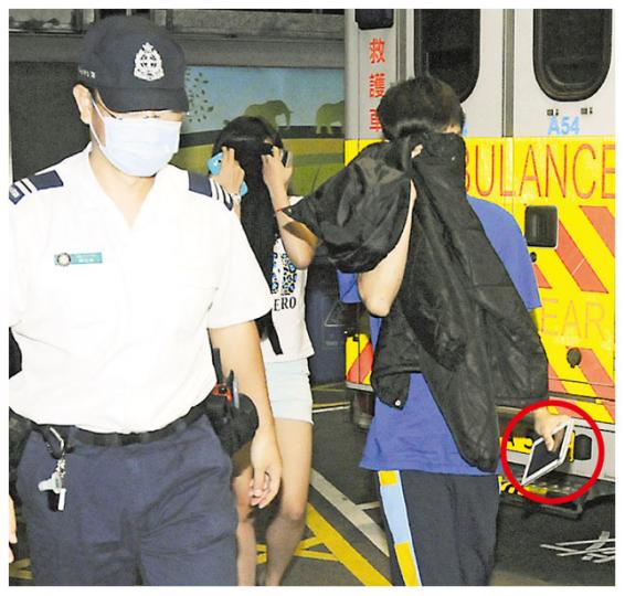 彩虹邨金碧樓被搶劫消夜的男事主（右藍衣者），事後由女親友陪同送院，其間不忘帶同平板電腦（紅圈示）。（蔡方山攝）