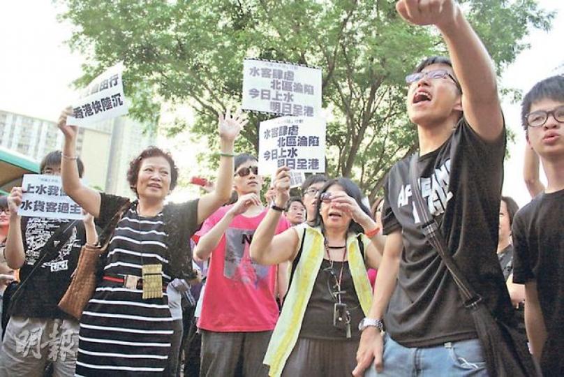 數百名北區居民昨午攜帶自製標語，包圍港鐵上水站，他們除指水貨客為上水帶來混亂，亦不滿內地自由行旅客充斥，令他們生活嚴重受阻。（楊德銘攝） 有自稱香港人者（右）昨午拖着幾部手拉車行經上水站，結果引來示威者喝倒彩，要警員將兩批人分隔開，才平息紛爭。（楊德銘攝）