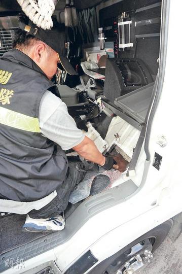海關人員展示案中藏於貨車駕駛室座椅下的走私暗格，消息稱若非X光檢測發現有異，單憑關員目測恐難發現暗格。（樊銳昌攝） 海關指揮官陳子達（圖）展示在貨車暗格檢獲的逾300部走私智能手機，總值82萬元。（樊銳昌攝）